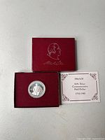 Coin in open presentation box with lid and certificate visible