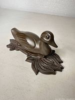 Side view of brass duck door knocker on leaf backplate