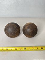 Pair of cast iron cannon balls with tape measure showing ~3.5 in diameter