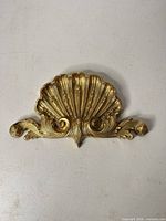 front view of gold shell motif metal applique