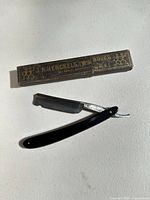 Razor fully open beside branded box