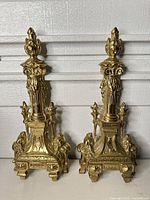 Full view of both brass andirons standing side by side