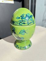 Full view of green porcelain egg vase showing pedestal and floral design