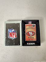 Front view of lighter in open display box next to NFL sleeve