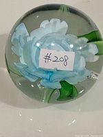 Front view of glass sphere showing blue flower bloom and foliage