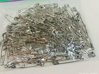 Pile of silver safety pins inside clear bag