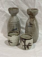 Front view of two sake bottles and two cups showing glaze and bamboo design
