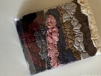 Front view of sealed package showing eight stacked satin scrunchies