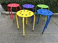 Front angled view of all five colorful stools on pavement