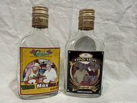 Front view of both souvenir flasks displaying custom labels and gold caps