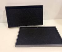 Two black velvet jewelry trays side by side, interiors visible