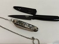 Gerber fixed blade knife with sheath alongside folding pocket knife with chain