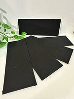 Front view of five black rectangular inserts, one upright, showing textured surface