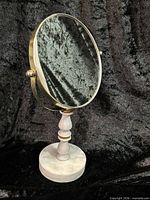 Full view of brass framed mirror on alabaster pedestal