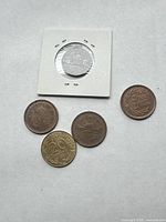 Group view showing three Japanese 10 Yen coins, one French 20 Franc, and 1968 U.S. nickel in cardboard flip