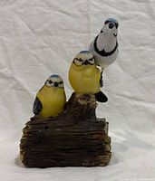 Front view of resin musical bird figurine showing two yellow birds on log and separate blue jay stake behind