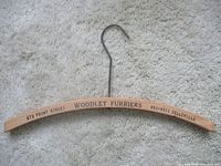 Full view of wooden hanger with printed text and metal hook