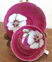 Cup displayed on saucer showing front orchid design and gold gilt