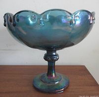 Side view of blue iridescent pedestal compote on wood surface