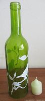 Full view of green wine bottle with painted bird and included votive candle