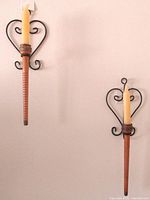 Two wall-mounted heart wrought iron sconces with wood candle holders