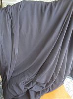 Full view of black sheer fabric draped to show length, color and drape