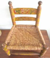 Front angled view of chair showing rush seat, painted back slats, turned legs
