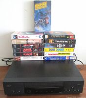 Full view of RCA VCR with stacked VHS tapes, shows quantity and titles