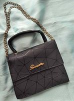 Front view showing spiderweb pattern, flap, gold script logo and chain strap