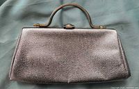 Front view of silver metallic clutch showing texture and clasp