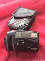 Front view of Pentax PC-100 camera beside Pentax case