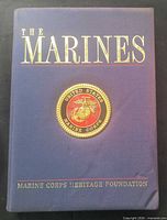 Front cover of clothbound book showing title and Marine Corps seal, visible corner damage