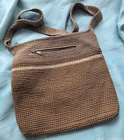 Front view showing overall bag shape, crochet texture, strap, zip pocket