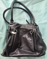 Front view showing logo, zip pockets, handles and hardware