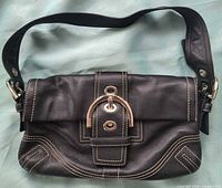 Front view showing flap, buckle clasp, stitching, strap