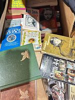 Top view of open box showing mix of books including Combat General, Class of ’44, Your Beauty Scope, How to Make Love All the Time, Bette Davis Mother Goddam and Reader’s Digest hardcovers