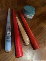 Group view of four taper candles and perfume candle tin on wooden surface
