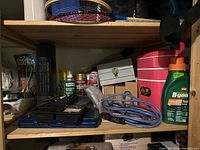 Overall view of shelf showing heater, sprays, pink tote, extension cord, lock box and B-Gon bottle