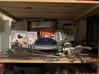 Overall shelf view with grill, meat grinder, utensils, boxed items