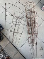 Two nested stacks of metal tomato cages on patio