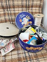 Overview of cookie tin with contents, ribbon roll, elastic spool and fabric