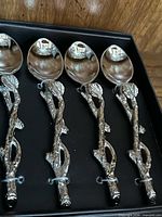 Close view of four silverplate spoons with branch handles tied in box insert