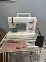 Front view of Janome Model 344 sewing machine with foot pedal and manual