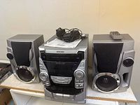 Full system showing main unit, both speakers, manual, remote and cables