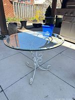full view of table on patio showing glass top and iron base
