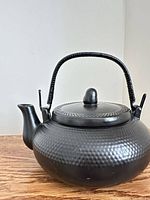 Side view of matte black cast iron-style teapot with handle and spout visible