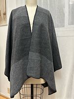 Front view of dark grey wrap on dress form showing open front and stitched edge