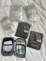 Five pouches: three sealed Air Canada kits, two black BACKY passport holders, navy opened Air Canada kit