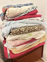 Stack of assorted folded queen sheets showing colors and patterns