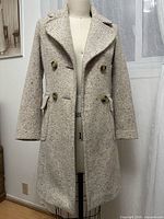 Front view of speckled beige tweed Benetton coat on dress form